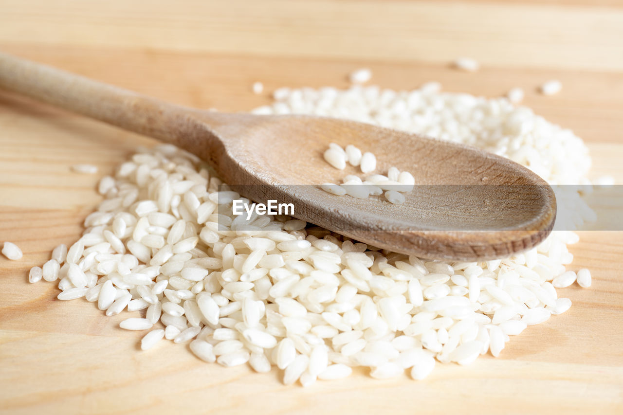 Rice on wooden spoon on wooden background. concept of cooking and food