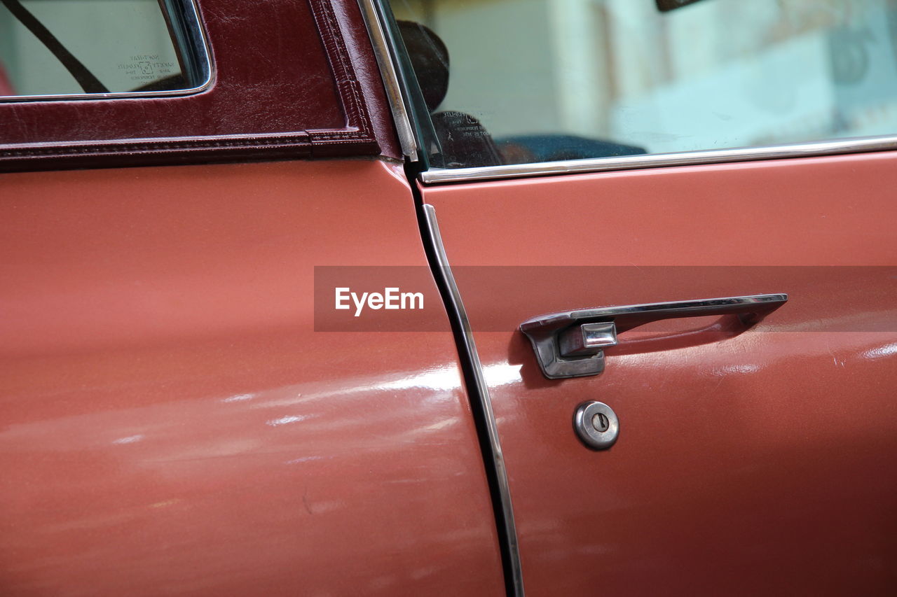 CLOSE-UP OF RED VINTAGE CAR ON ROAD