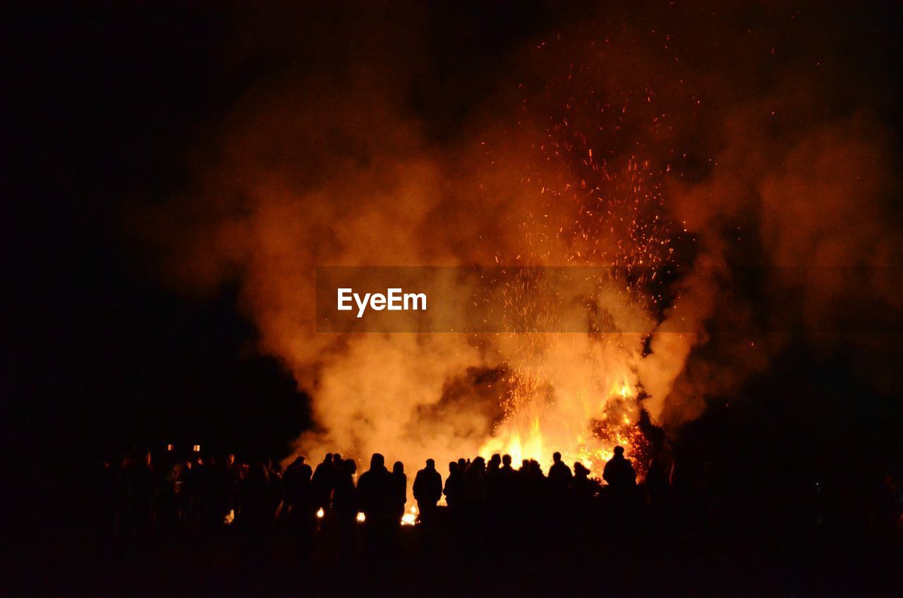 People watching lit bonfire at night during easter