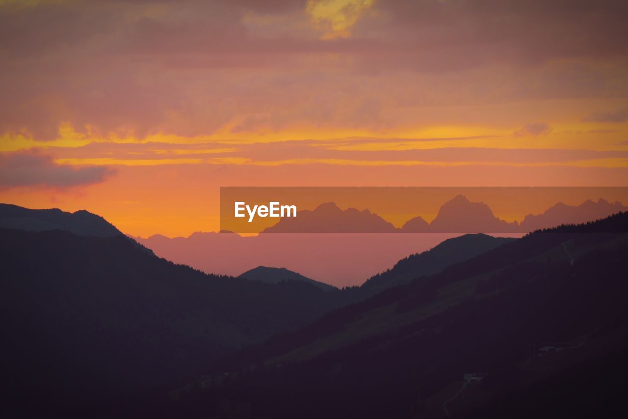 Scenic view of silhouette mountains against orange sky