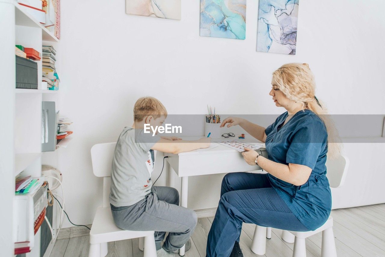 Speech therapist engaging with boy in nonverbal communication training, cognitive skills development