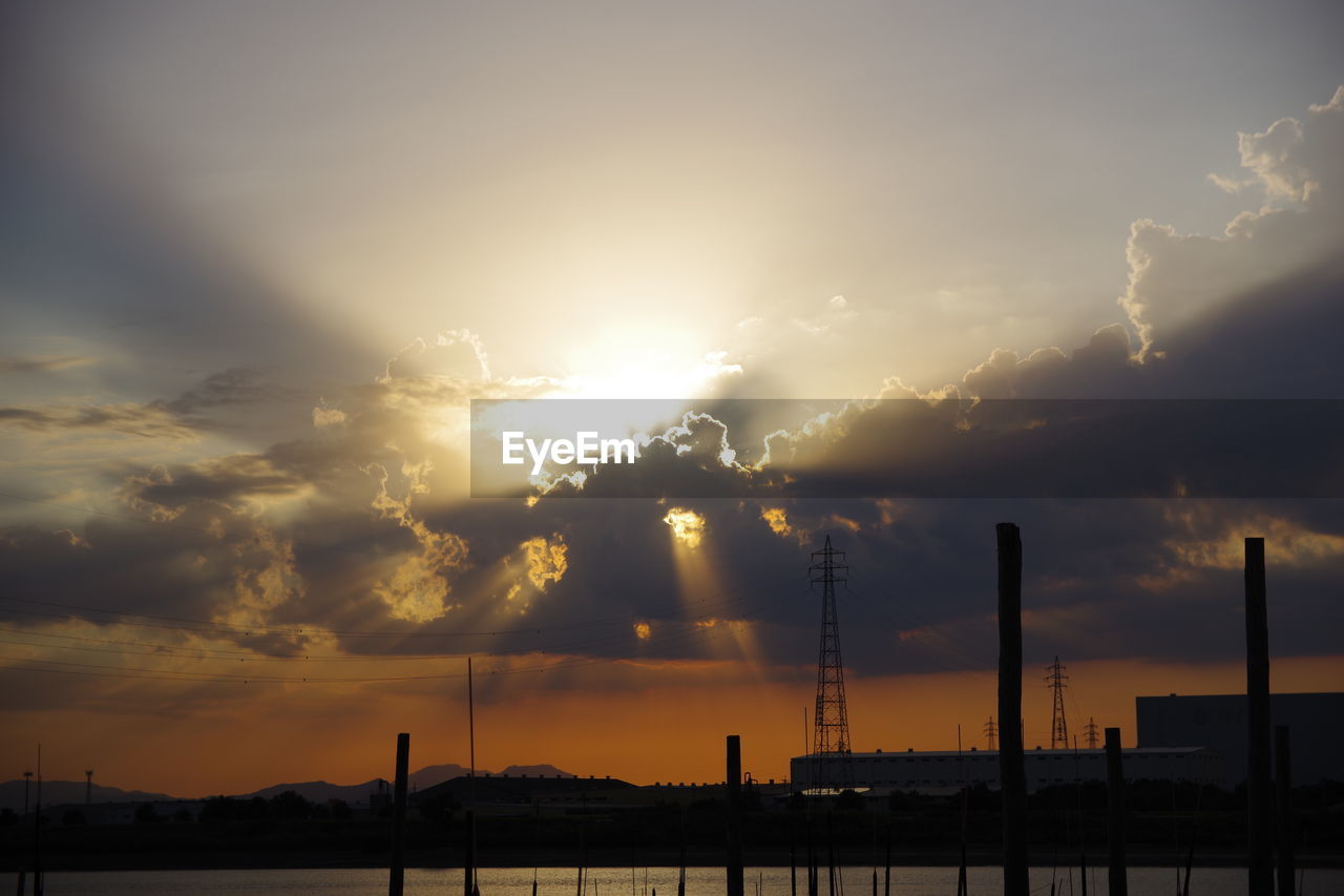 Sunlight streaming through silhouette of city during sunset