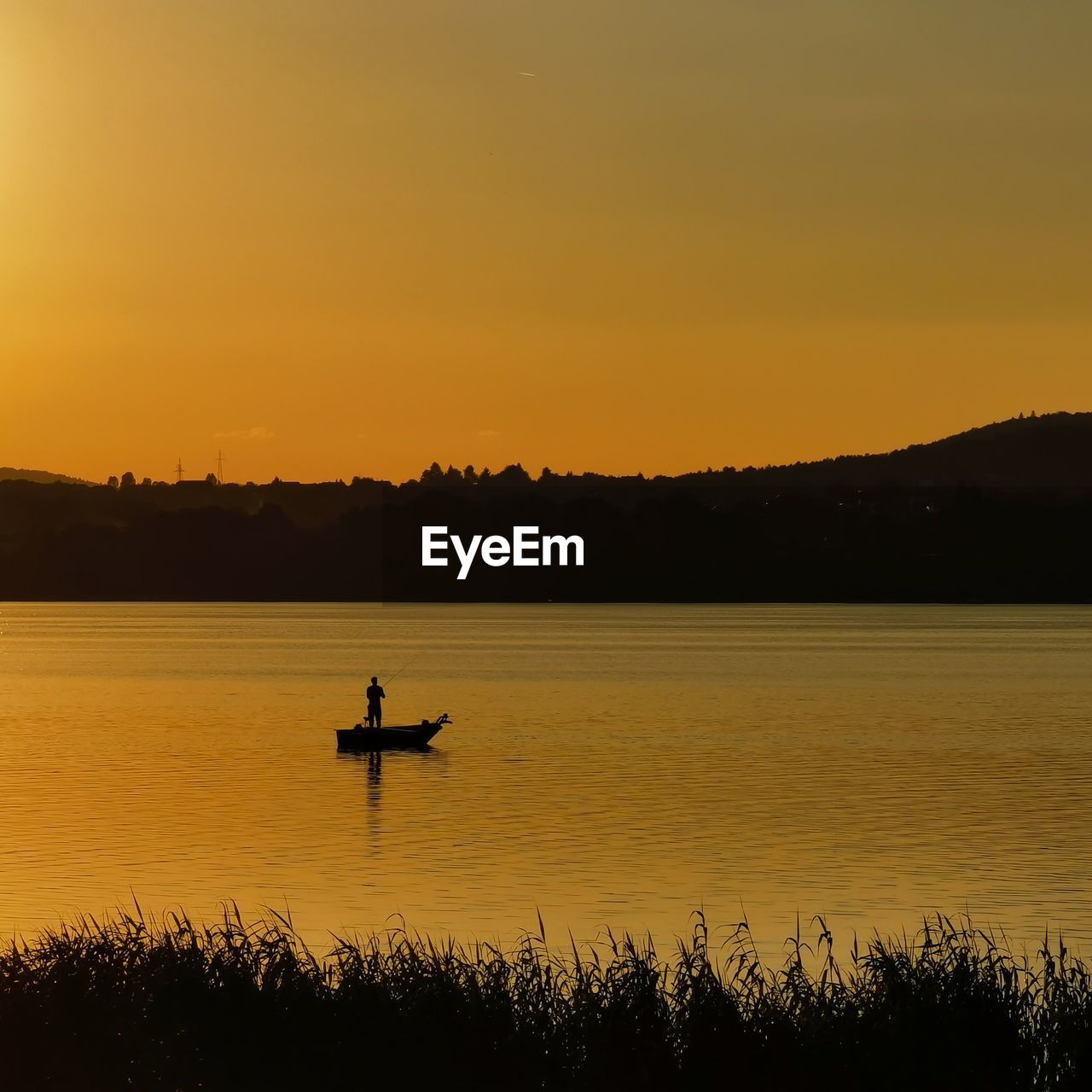 SILHOUETTE BOAT IN LAKE AGAINST SKY AT SUNSET