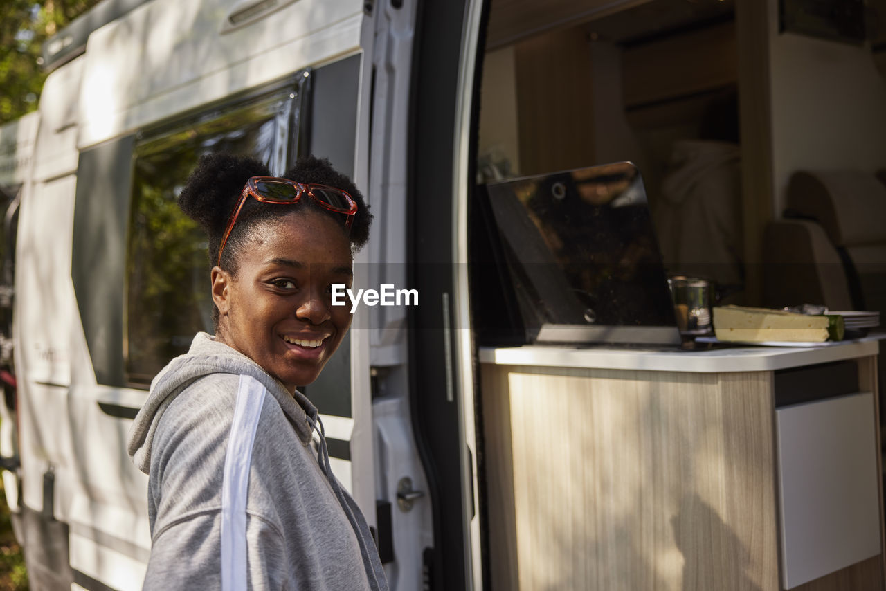 Portrait of smiling woman in front of camper van