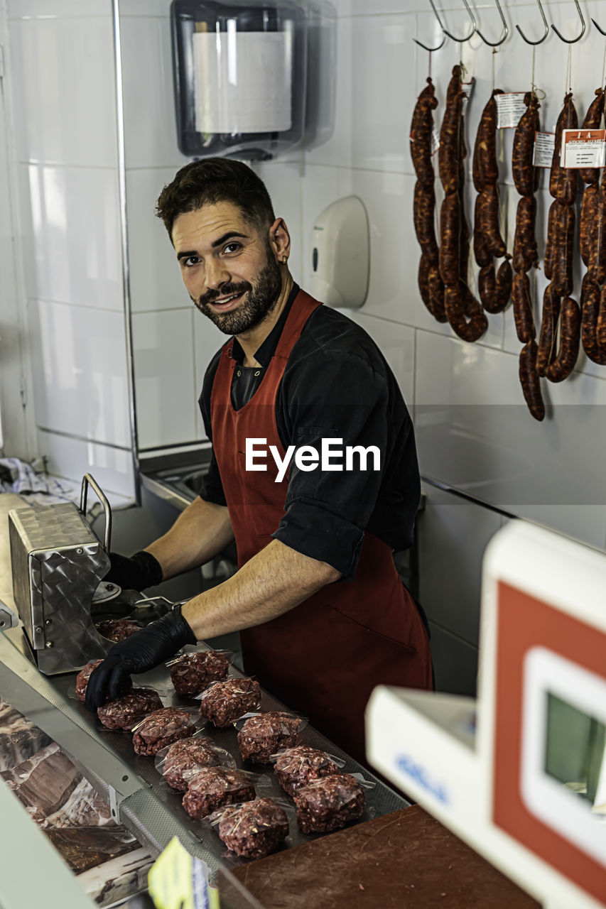 Butcher making raw beef burgers in butchers shop.