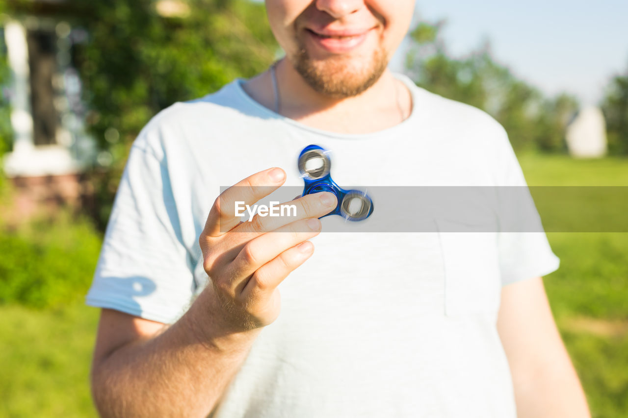 midsection of man holding dentures while standing outdoors