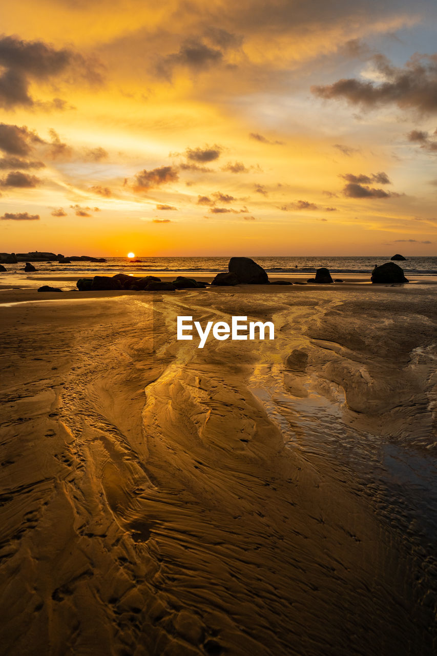 SCENIC VIEW OF BEACH AGAINST SKY AT SUNSET