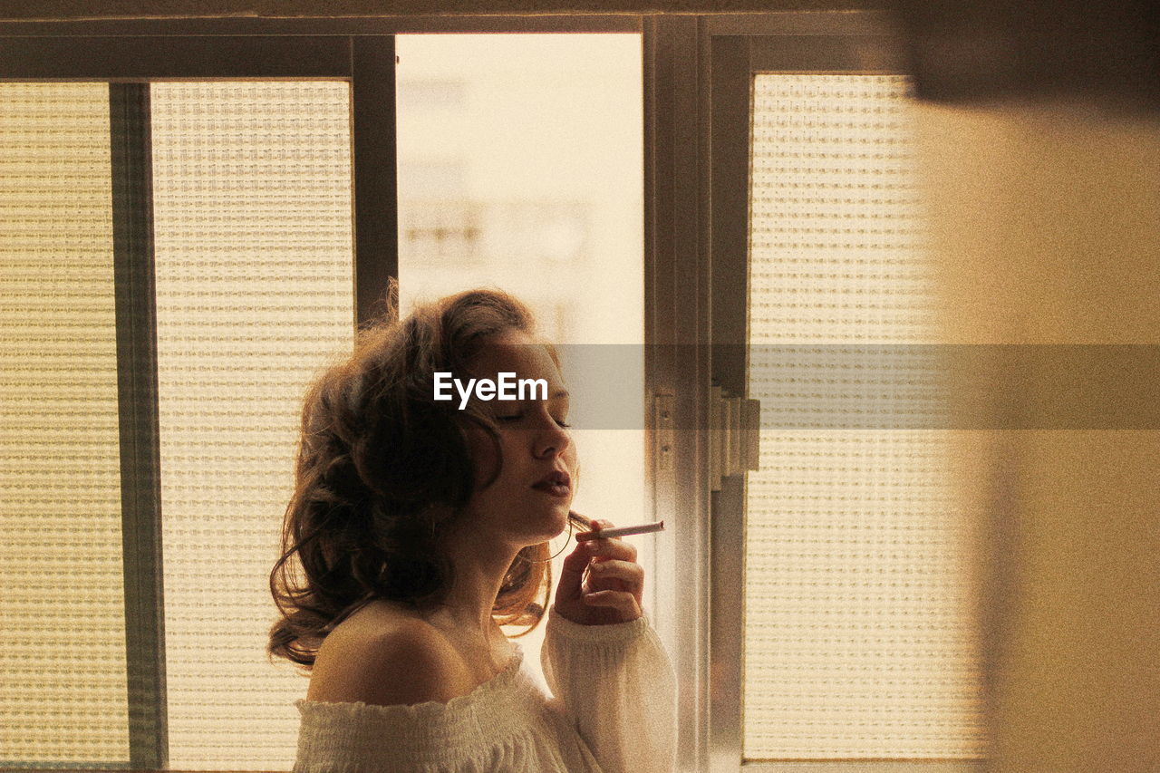 Woman smoking cigarette by window