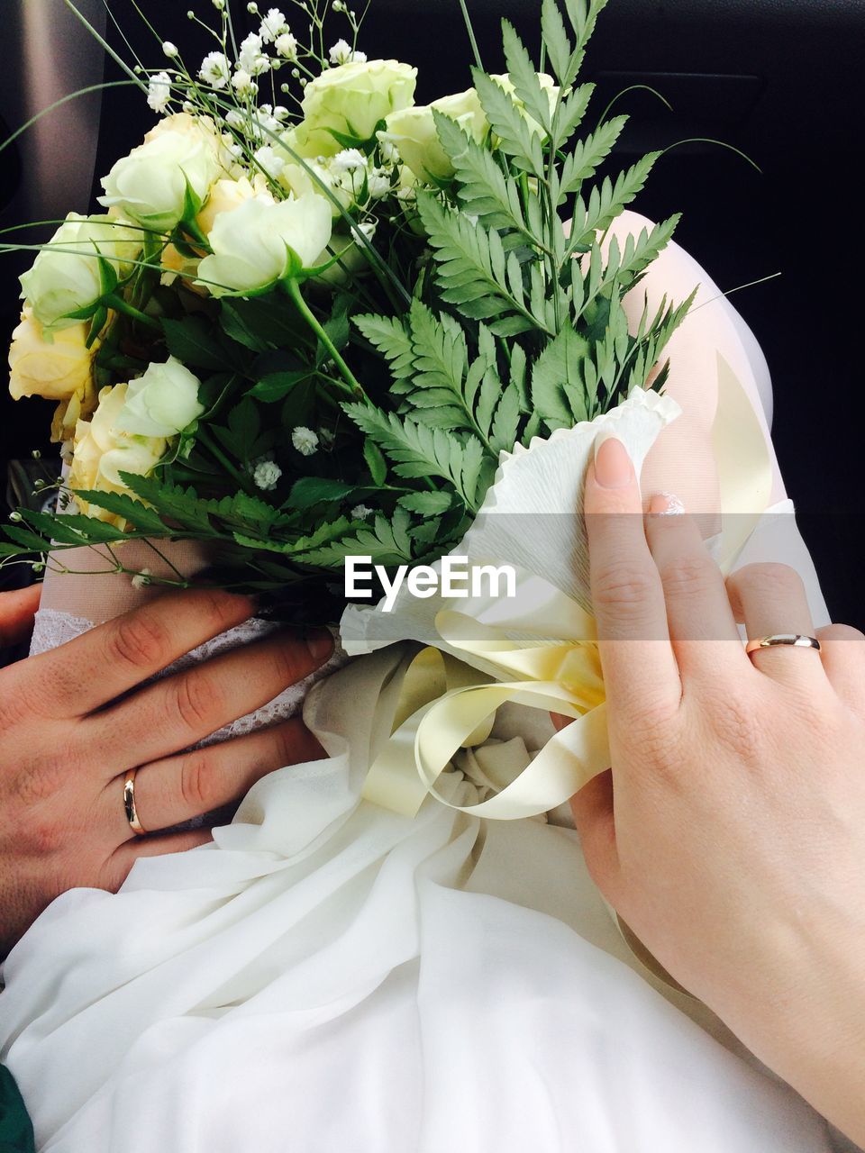 Cropped hands of bride and groom holding bouquet