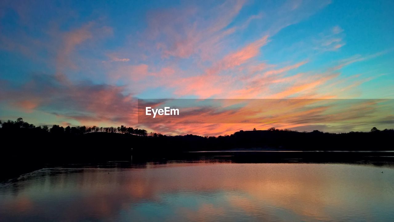 Scenic view of calm lake against cloudy sky