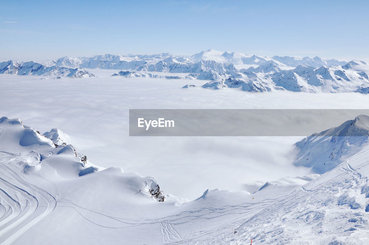 Fog and mist above in the valley at winter in snow covered mountains