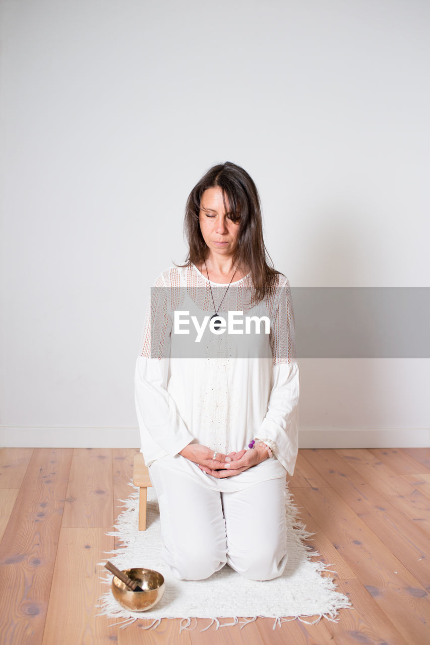 Beautiful woman during a meditation sesion. dressed with white clothes, empty room, wooden floor