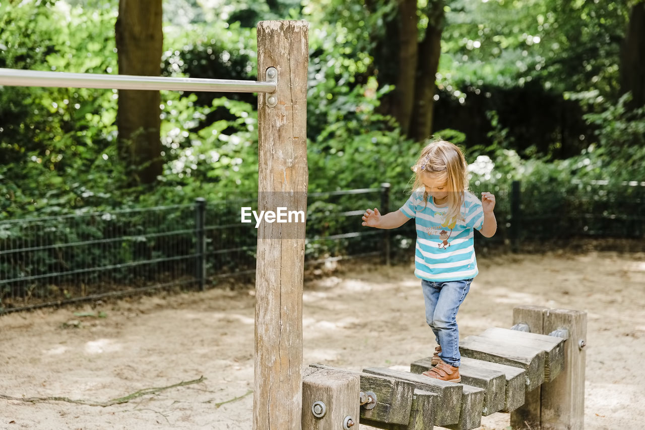 Full length of girl standing standing on play equipment in playground