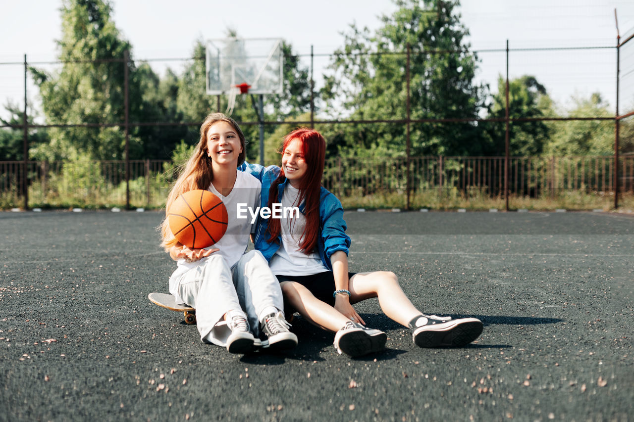 A couple of teenage girls on a sports street court with a basketball lifestyle 