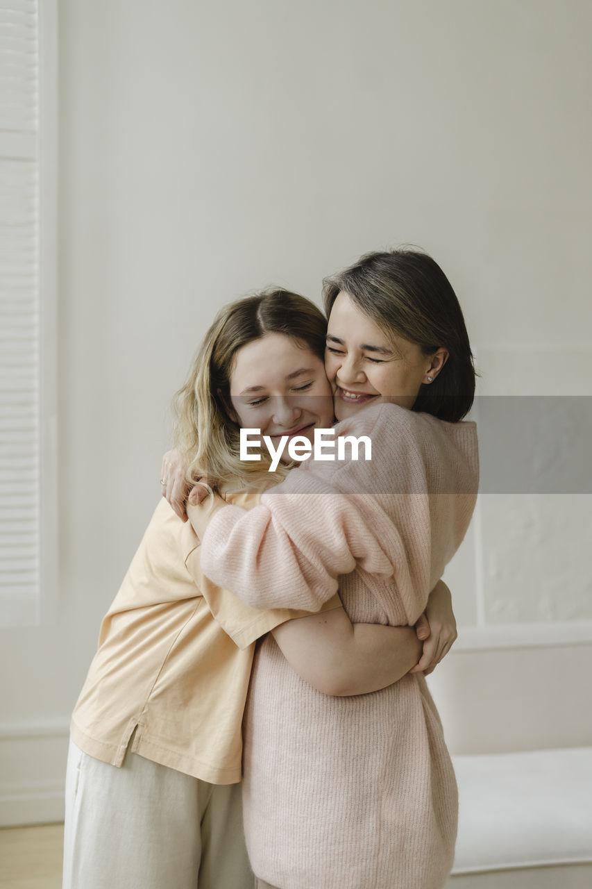 Happy mother and daughter embracing in living room