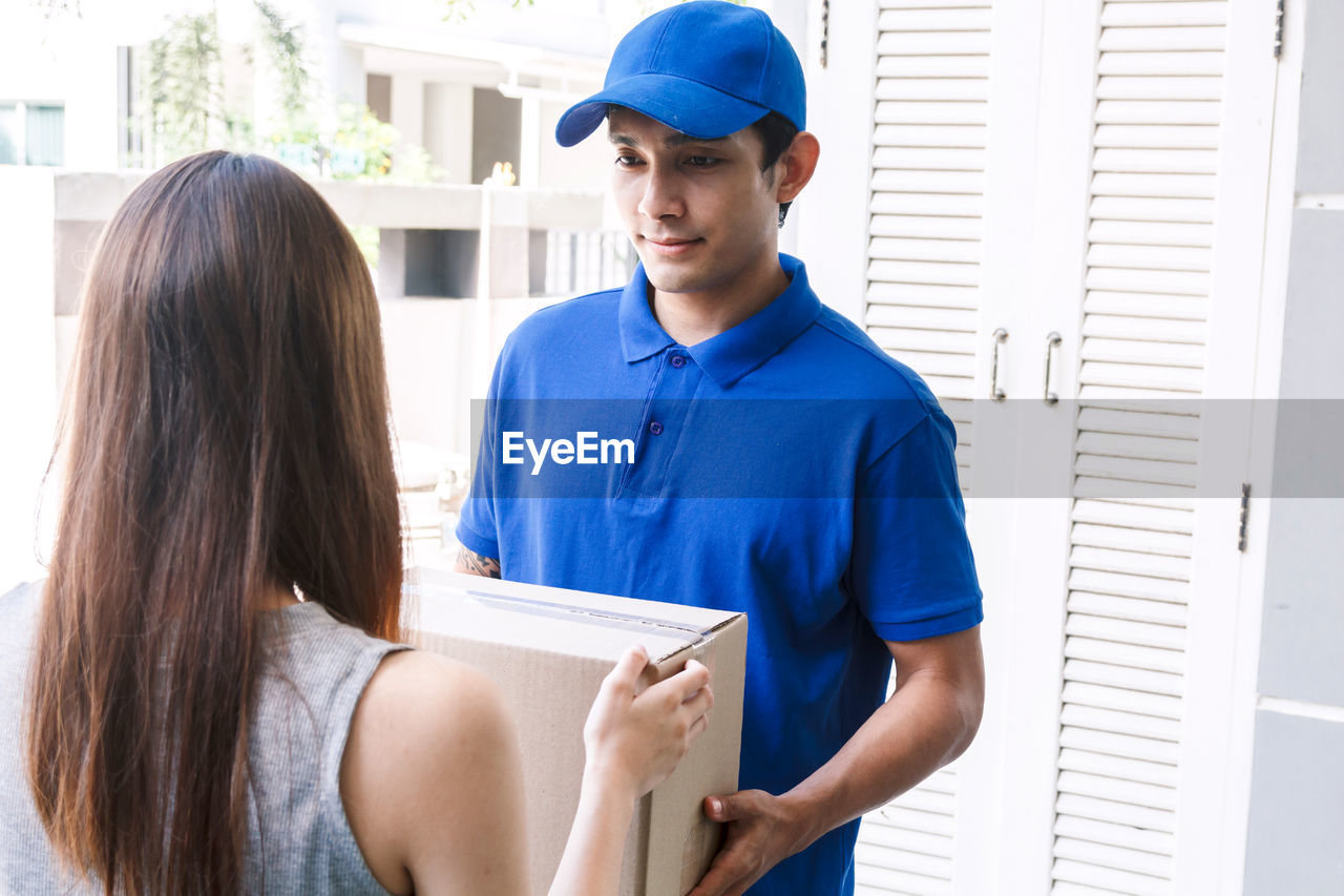 Woman receiving package from salesman while standing at doorway