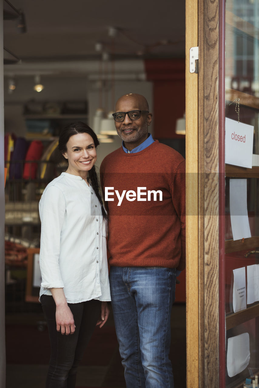 Portrait of smiling owners standing at store entrance