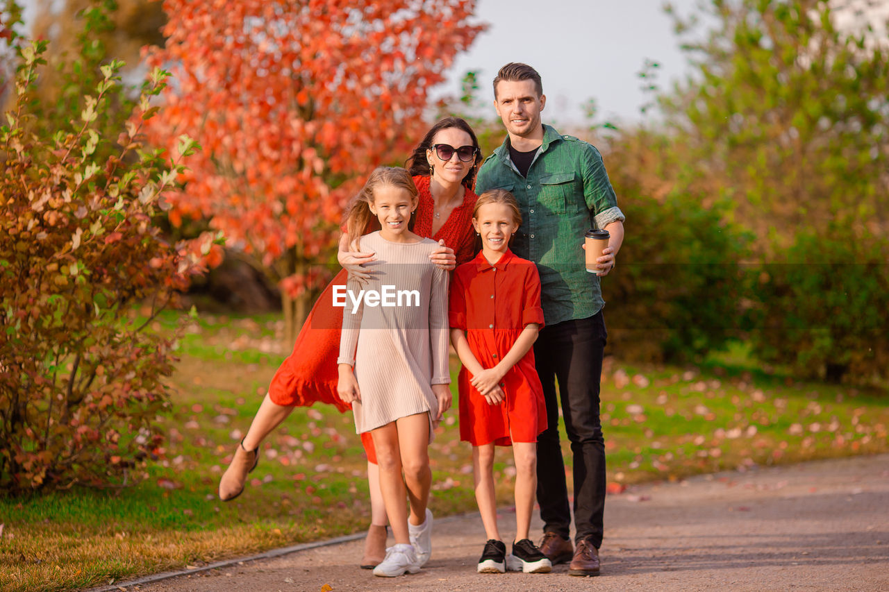 FULL LENGTH PORTRAIT OF FATHER WITH DAUGHTER AGAINST PEOPLE