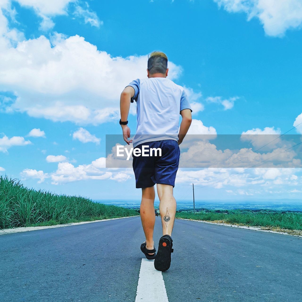 Rear view of man standing on road against sky