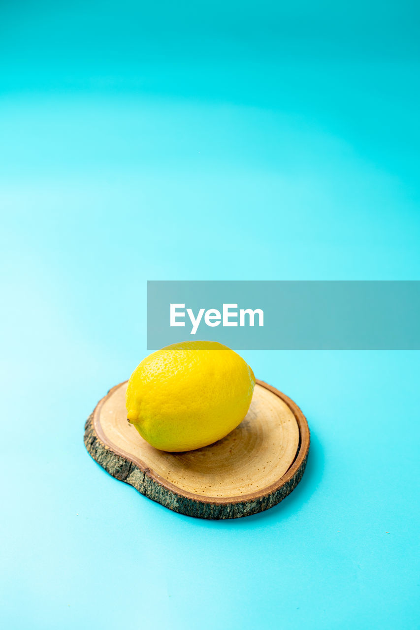 A lemon photographed on a light blue background.