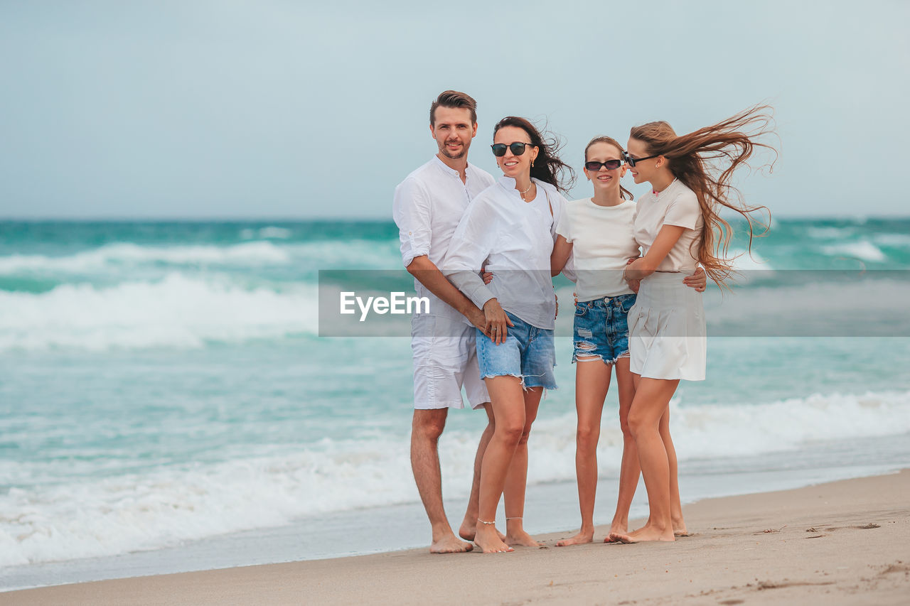 full length of friends standing at beach