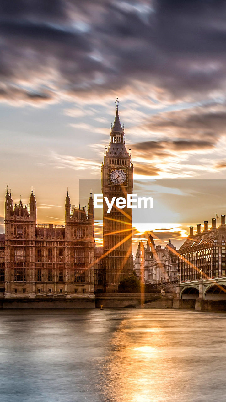 View of big ben from river against cloudy sky