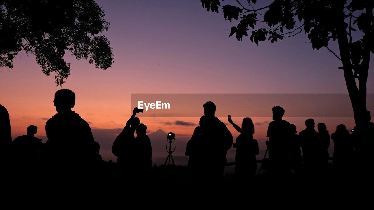 Silhouette people against sky during sunrise