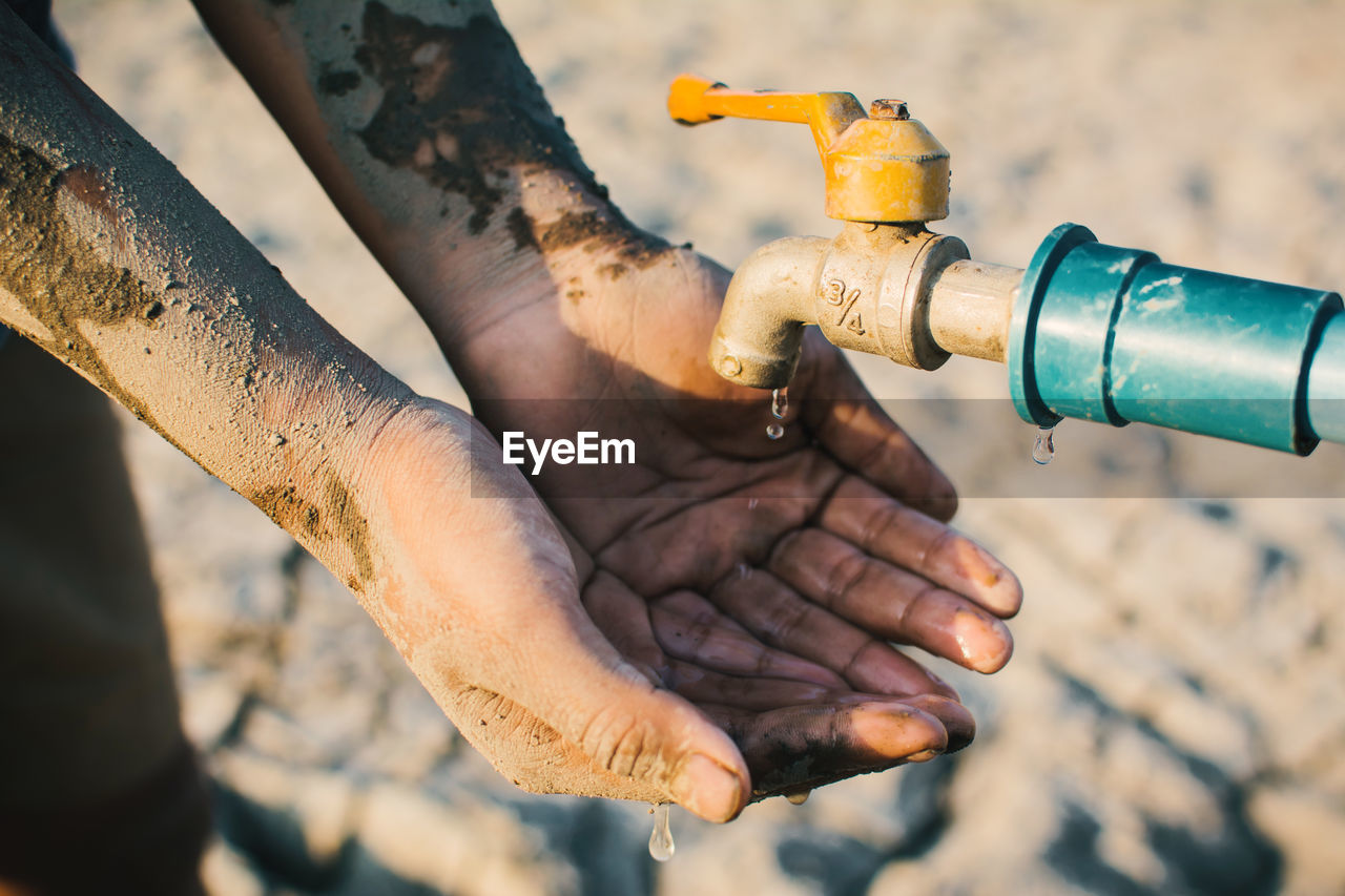 High angle view of hand by tap on barren field