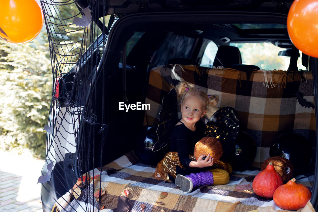 Cute little girl celebrating halloween in car trunk. stay home celebration. autumn holidays.