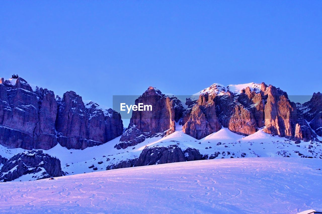 Low angle view of snow covered rocky mountains against sky