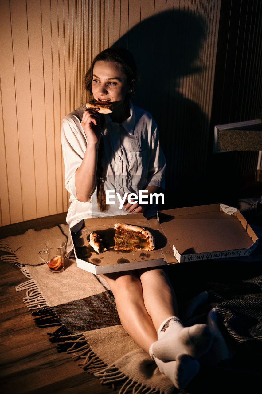 Loneliness in christmas holidays, valentines day. young alone woman in pajamas eating pizza near