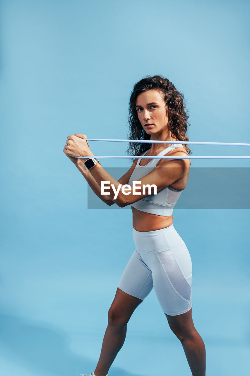 Determined athlete exercising against blue background