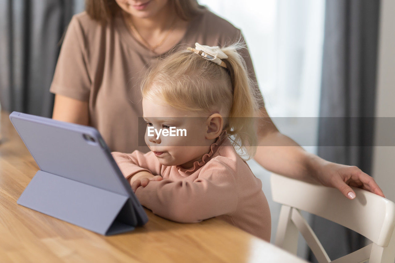 young woman using laptop while sitting on table