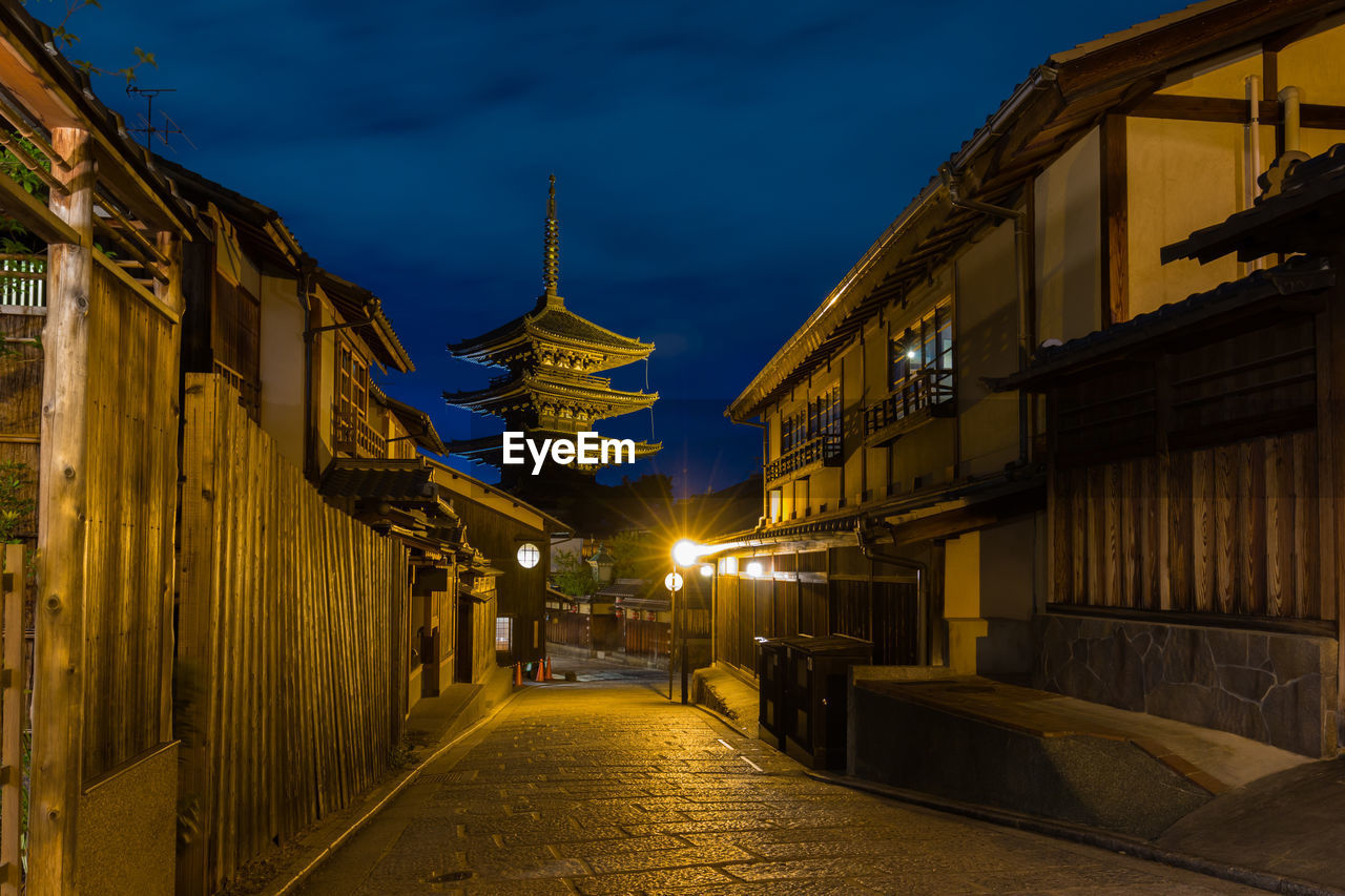 Street amidst illuminated buildings against sky at dusk