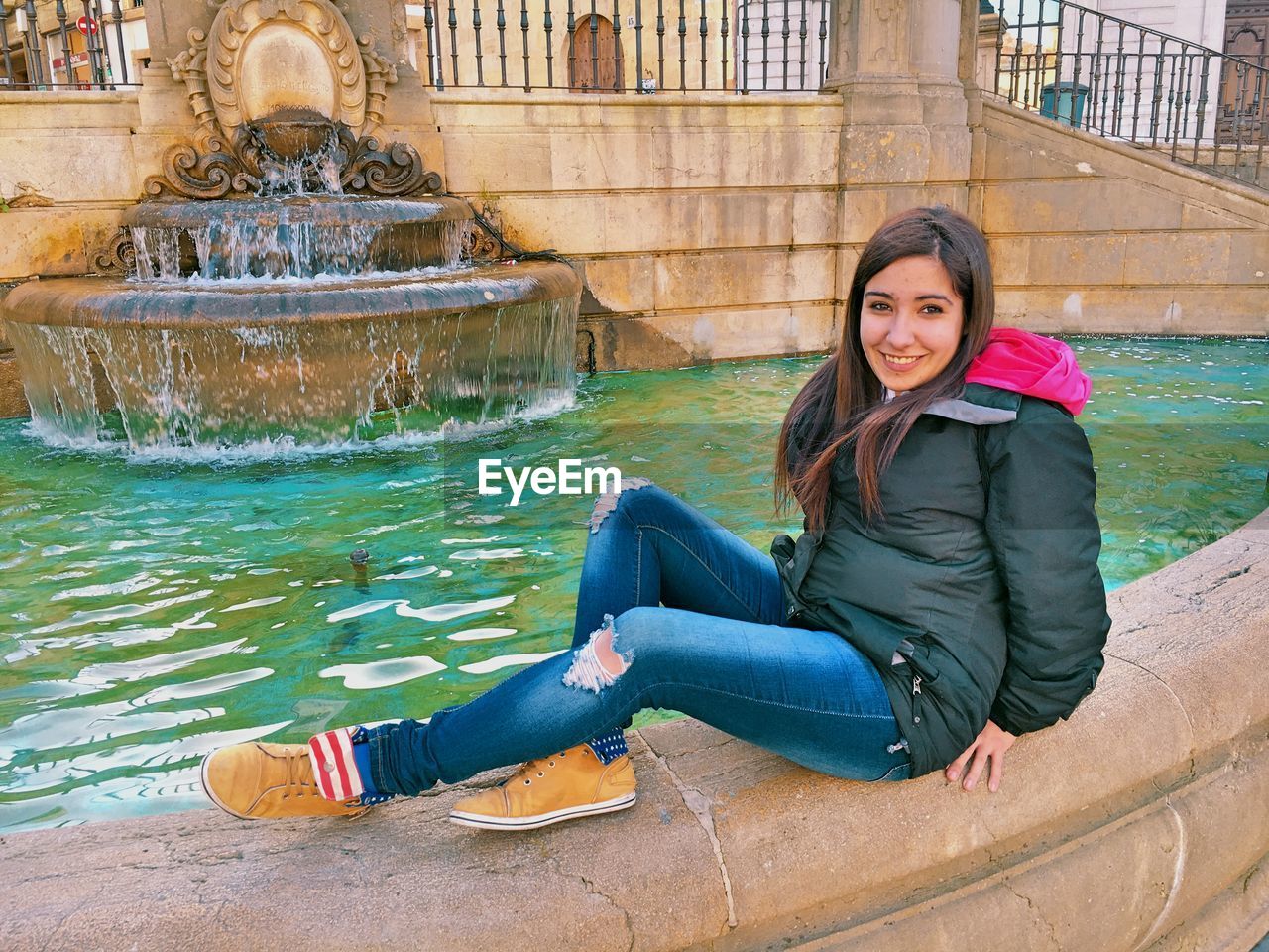 Portrait of smiling woman sitting by fountain
