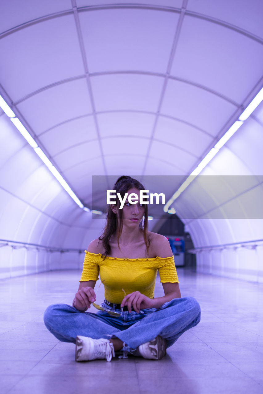 Full length of young woman sitting on floor in tunnel