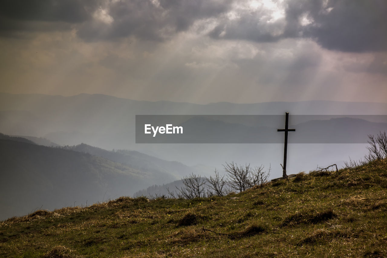 Cross on mountain against sky