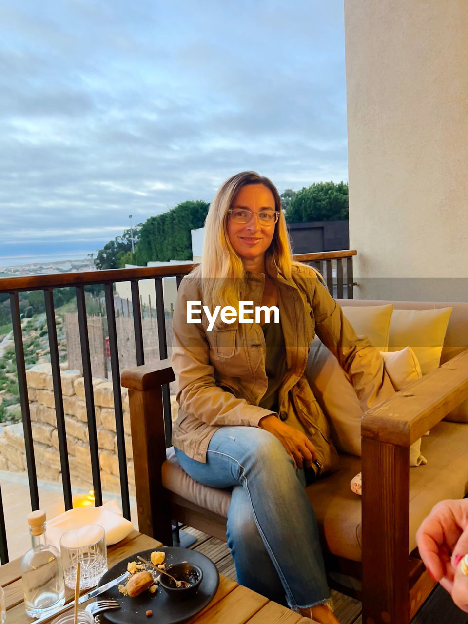 Portrait of young woman sitting on chair against sea