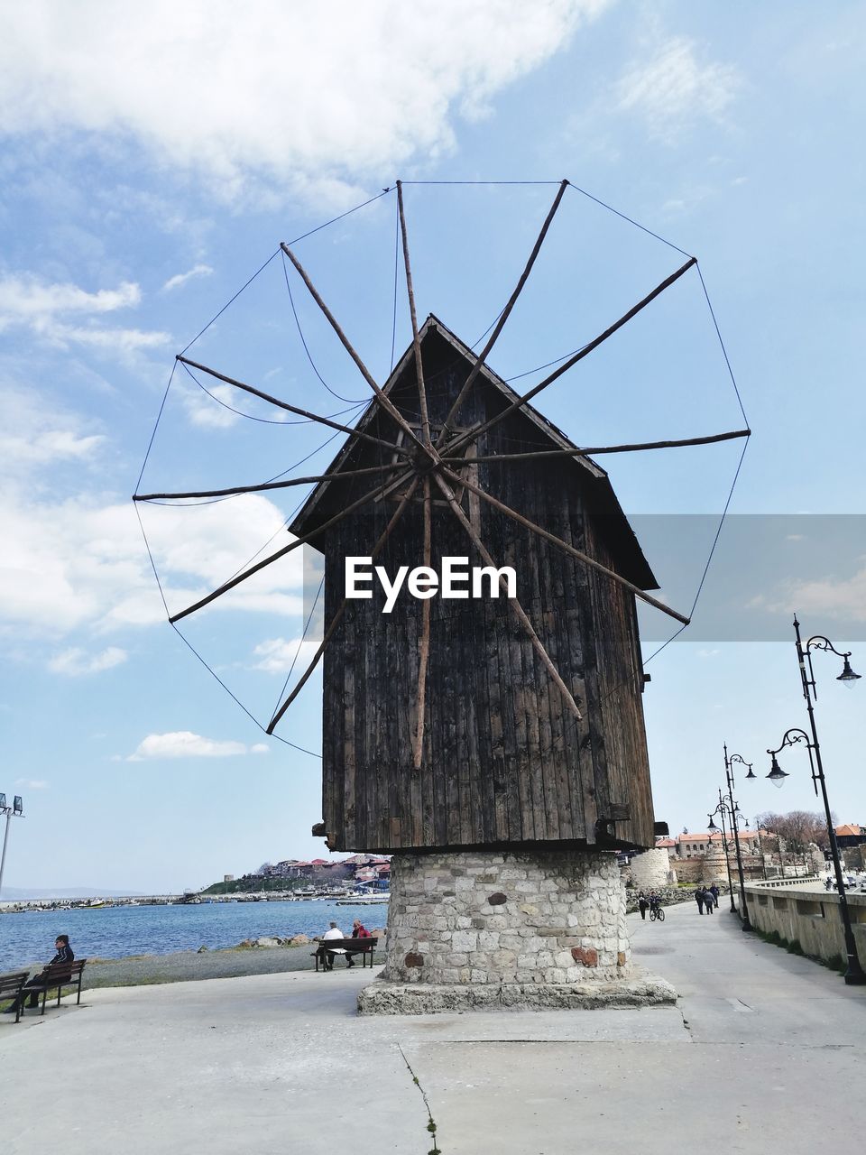 Traditional windmill on beach against sky