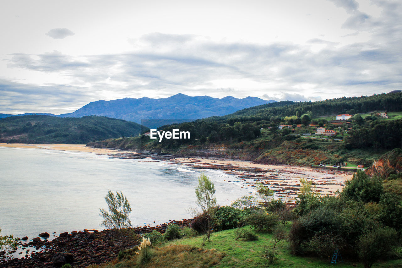 Scenic view of sea and mountains against cloudy sky