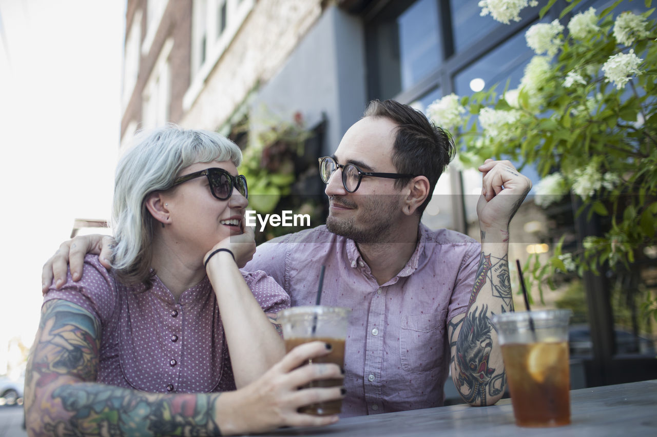 Young couple sitting in outdoor cafe drinking ice tea