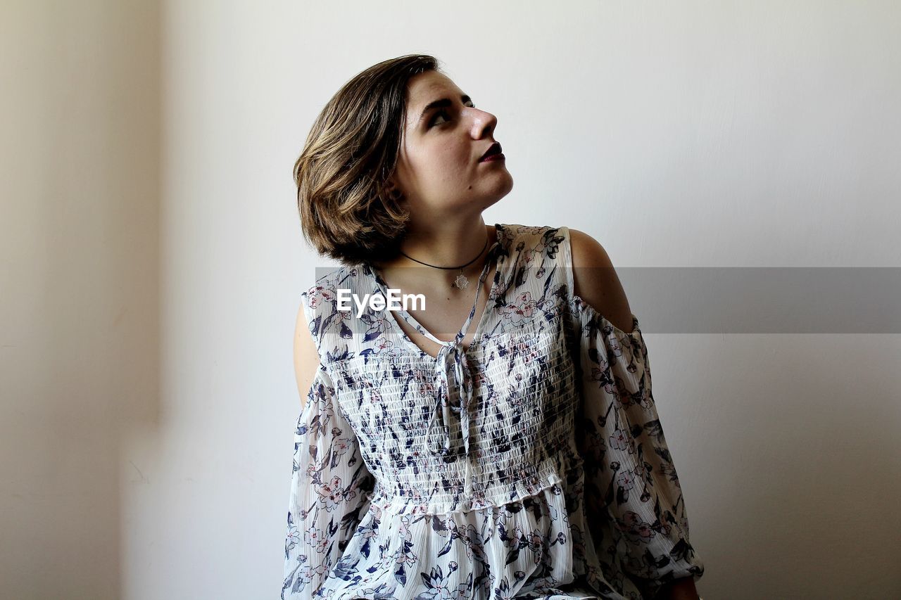 Young woman standing against white wall