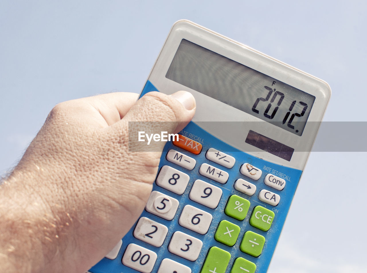 Cropped image of man holding calculator against sky