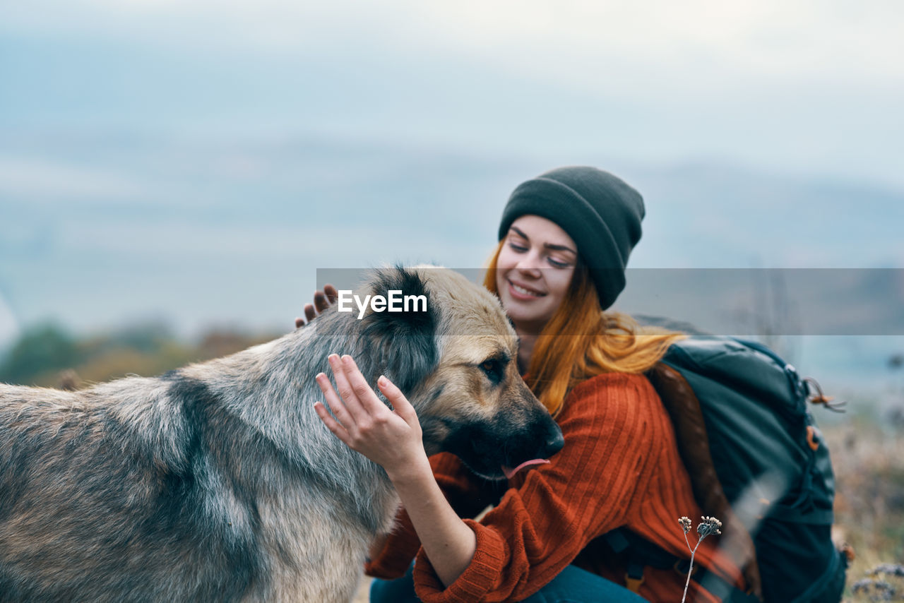 PORTRAIT OF WOMAN WITH DOG AGAINST SKY DURING SUNRISE