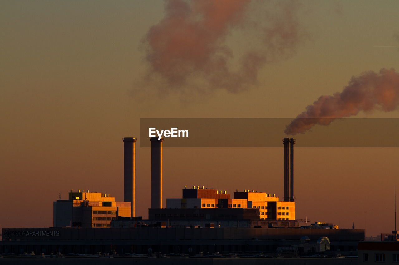 Smoke emitting from industry against sky during sunset