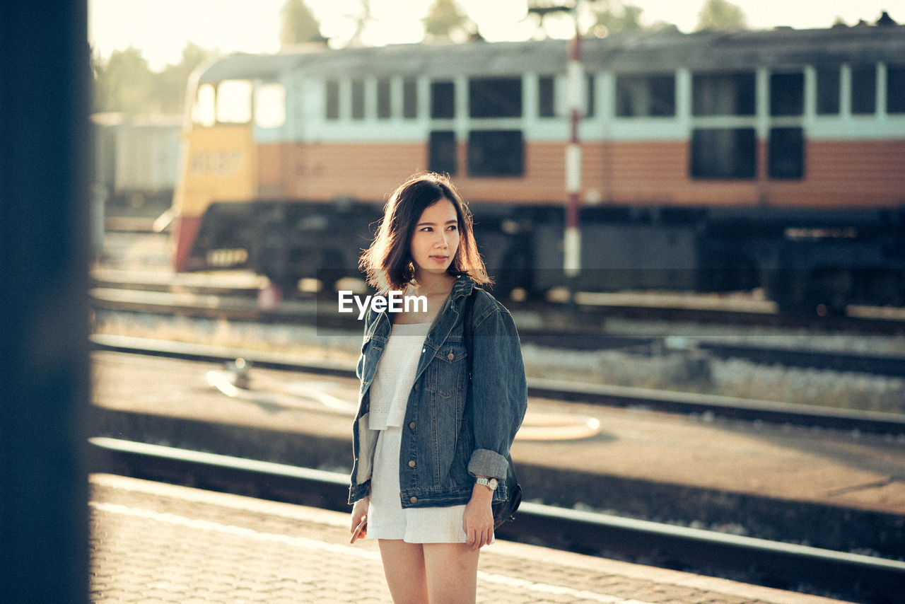 Young woman standing at railroad station