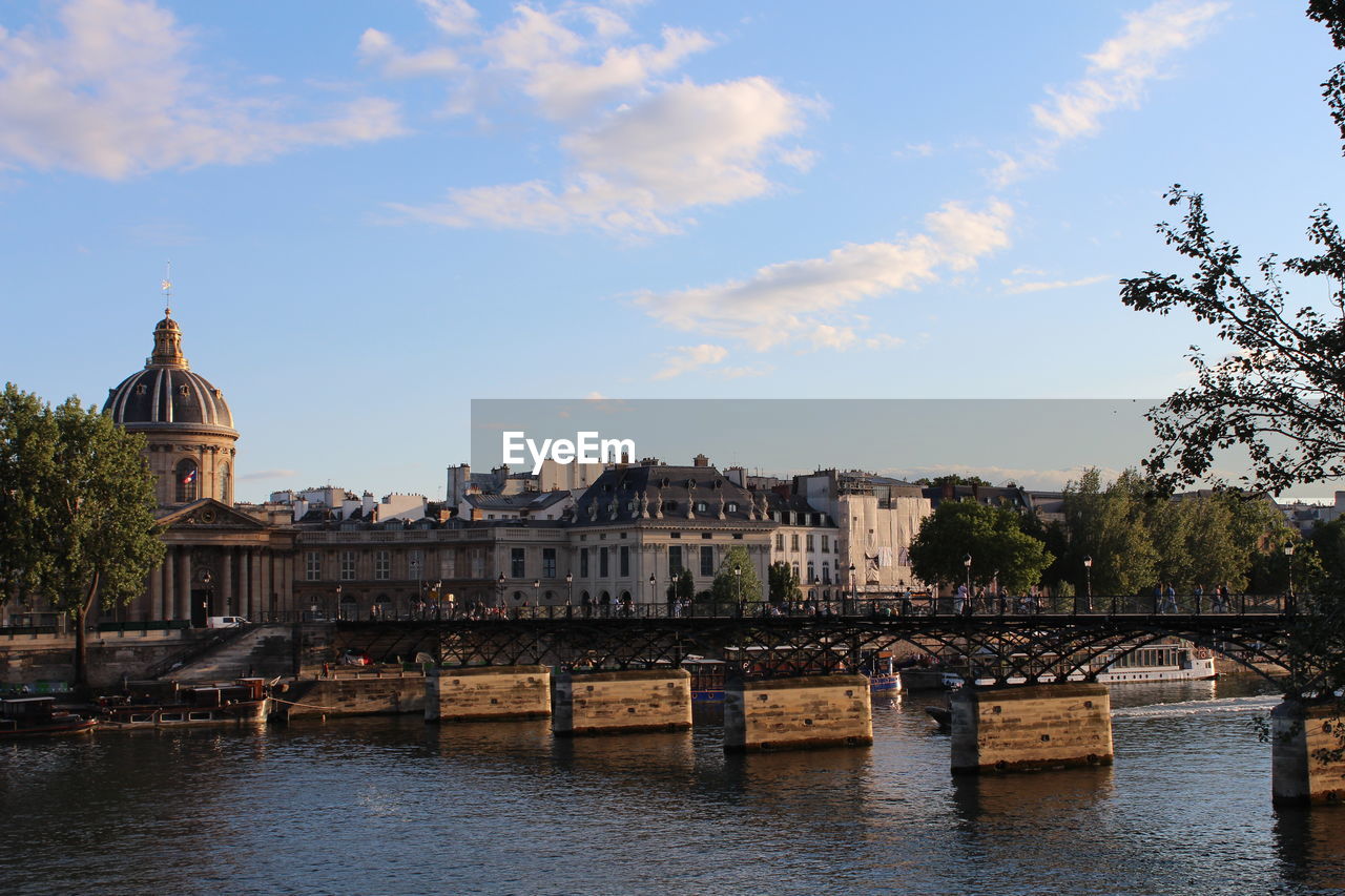 Buildings at waterfront against cloudy sky