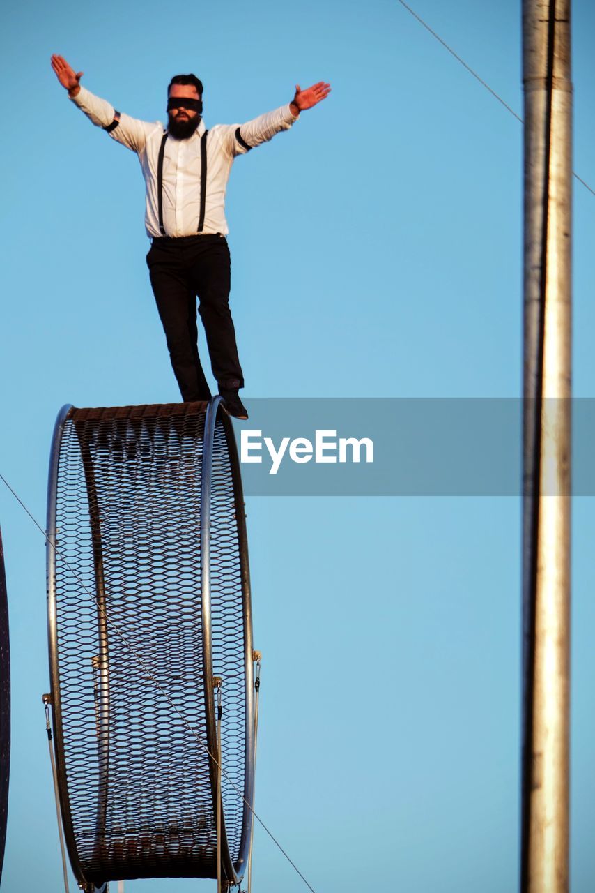 LOW ANGLE VIEW OF YOUNG MAN STANDING AGAINST SKY