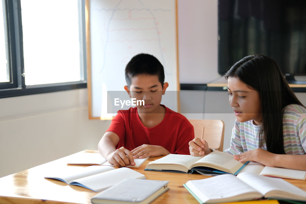 Asian boy girl student studying doing homework in library. learning education at school