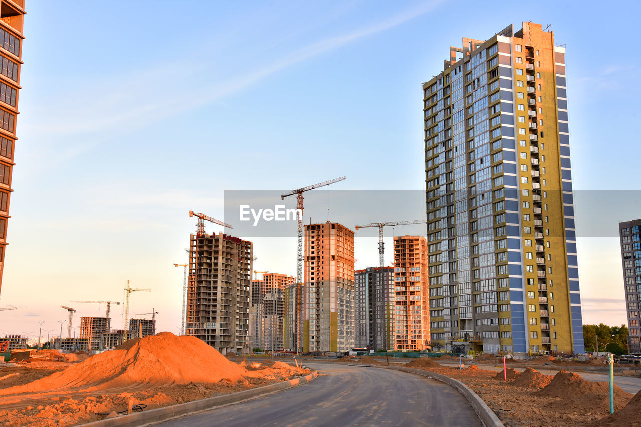 View on the large construction site with tower cranes and buildings on sunset 